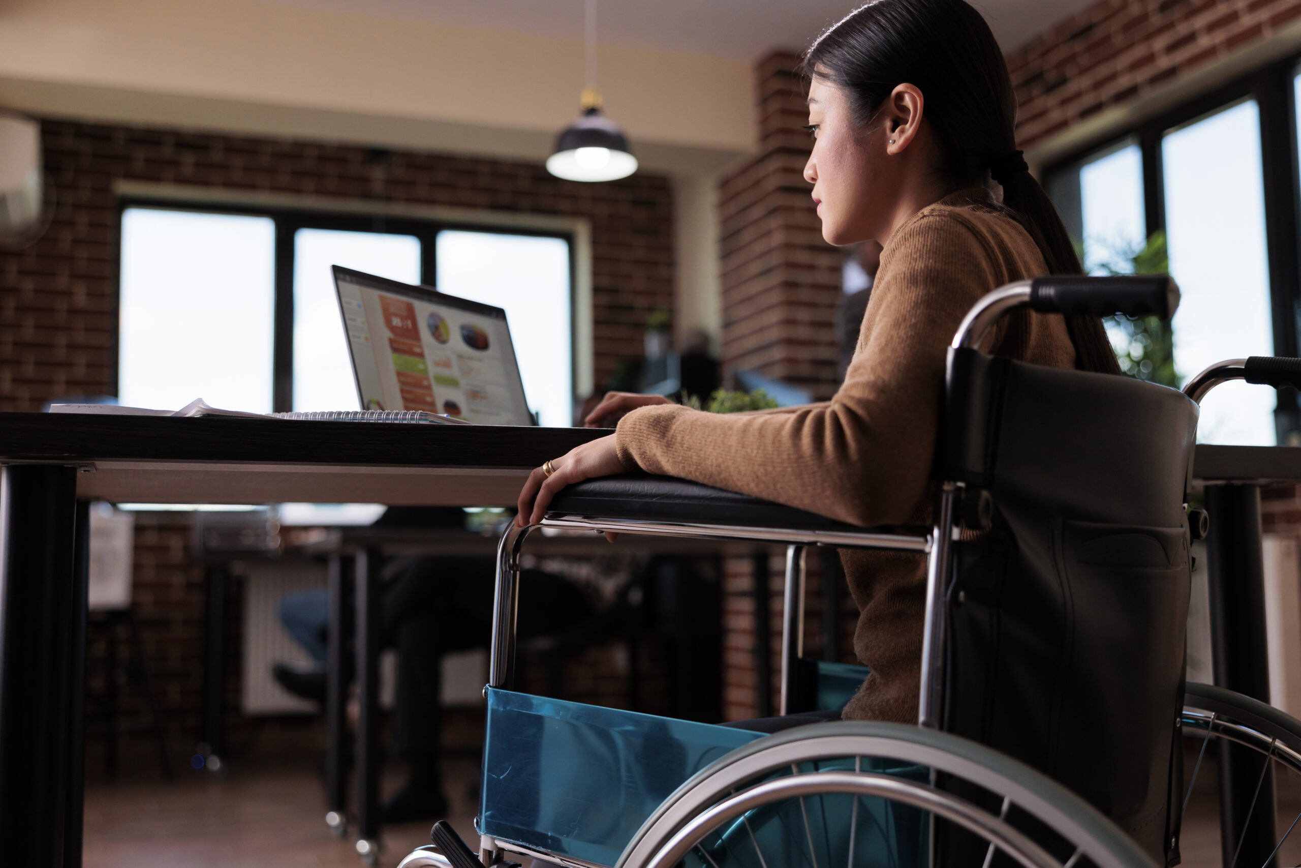 Freelancer with a physical impairment working on a laptop in an accessible office