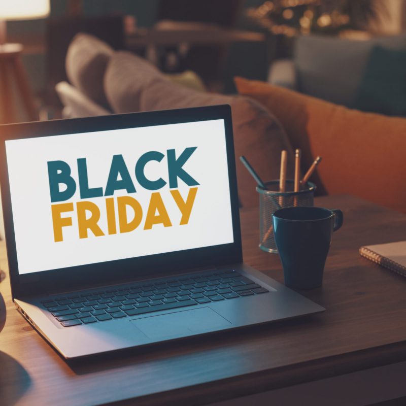 Black Friday sale promotional ad on a laptop screen, living room interior in the background